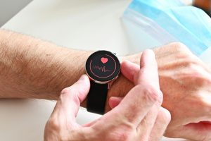 A man using a heart rate tracker to monitor cardiovascular health while following a nutritionist-approved heart-healthy diet