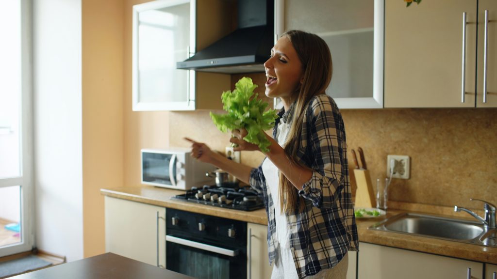 Woman preparing fresh vegetables in a kitchen as part of a holistic nutrition and health reset program.