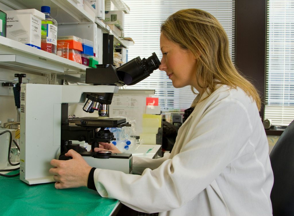 woman looking at dna under a microscope while doing genetic testing for metabolic markers